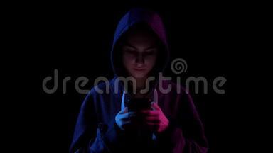 一个戴着兜帽，手里拿着电话的年轻女子。 黑客通过电话攻击。 蓝色和红色的光落在